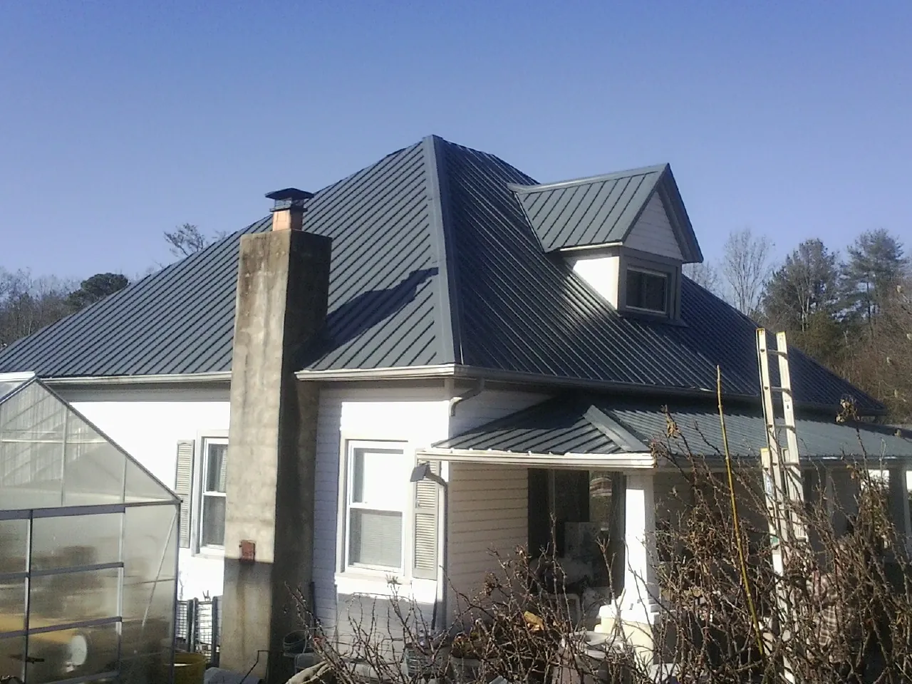 Dark blue standing seam metal roof on a white farmhouse with dormer — Slate & Tile Roof Repair by Roofing Brothers in Gibbsboro