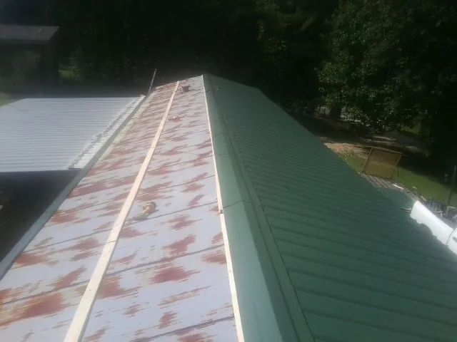 Old rusted panels beside newly installed green metal roofing — Wind Damage Roof Repair by Roofing Brothers in Gibbsboro
