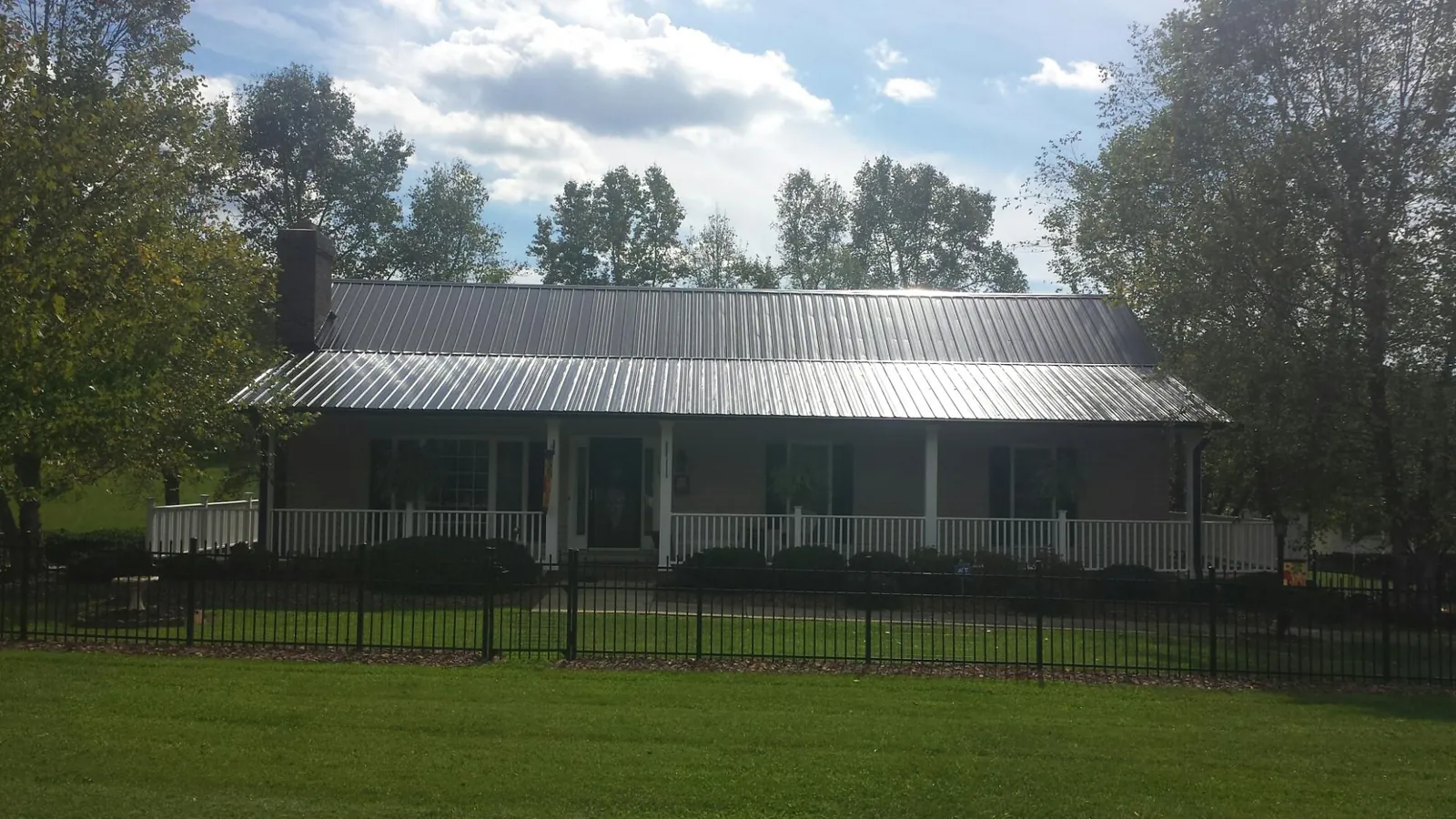 Gray metal roof on a brick ranch with a full width front porch — Gutter Guard Installation work by our crew in Gibbsboro
