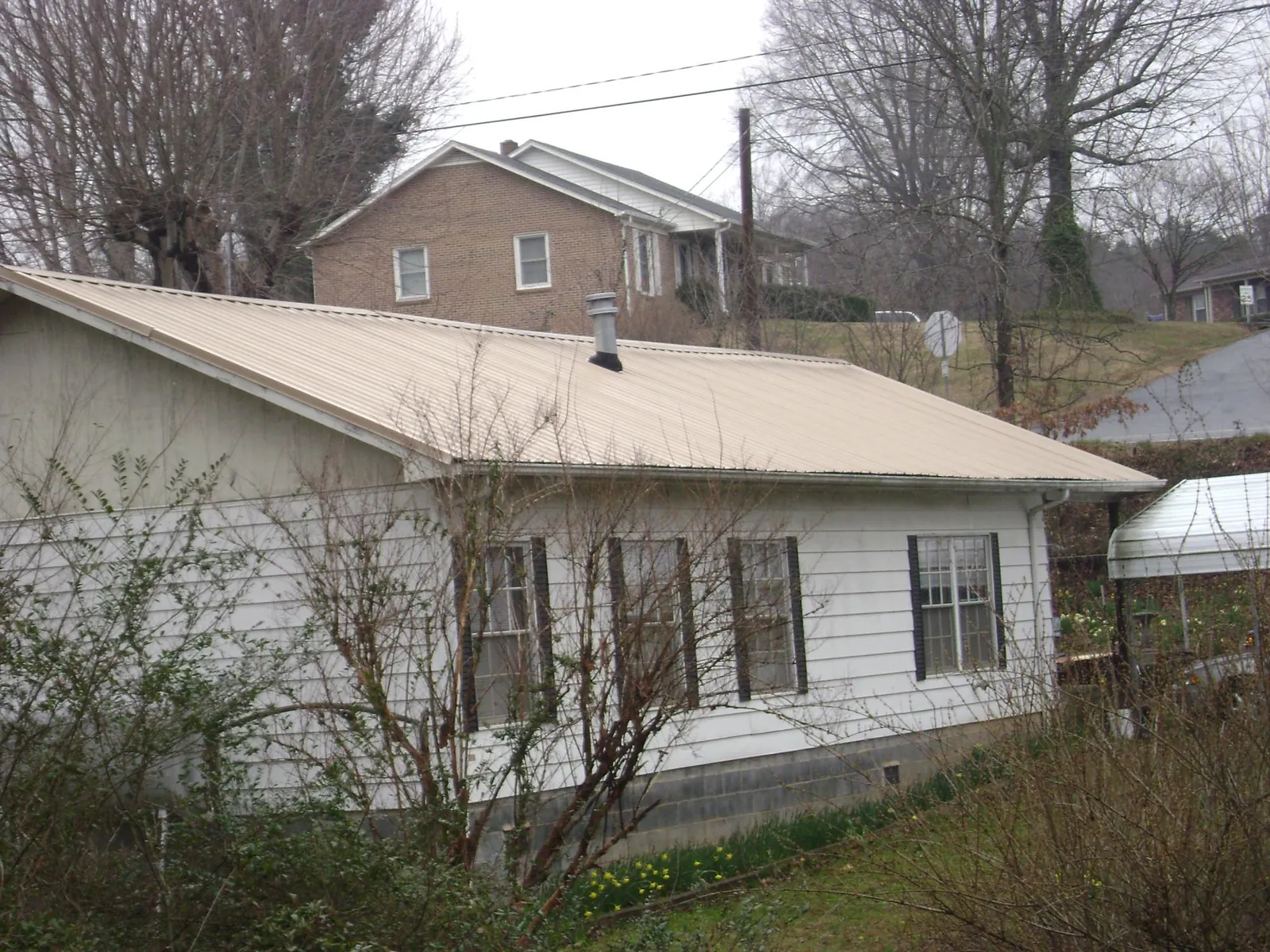 Tan metal roof on a white sided house set into a hillside — Commercial Roofing by Roofing Brothers in Gibbsboro