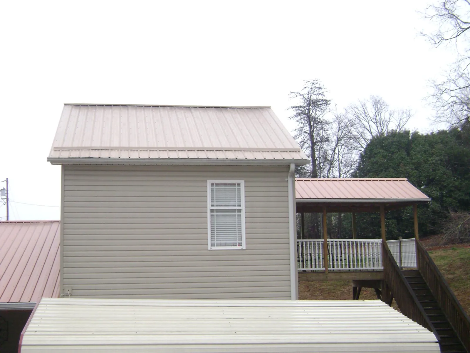 Tan metal roofs on a two story addition and attached porch, from a Roof Replacement job in Gibbsboro
