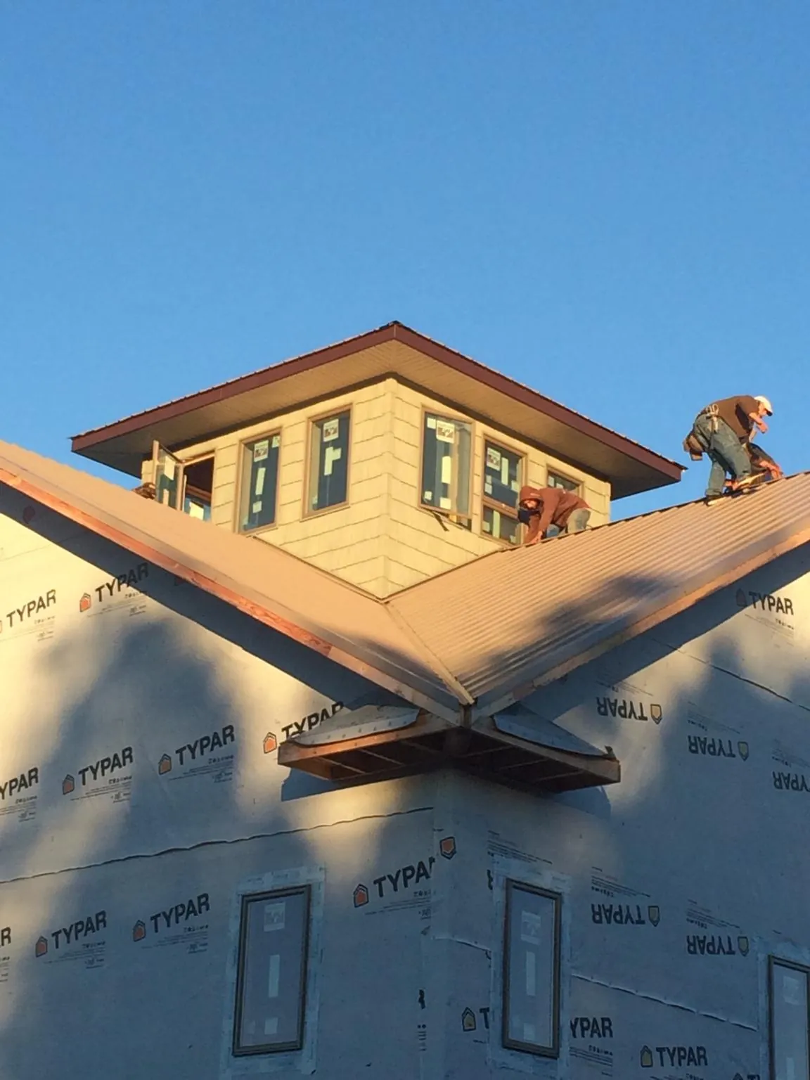 Roofers working around a rooftop cupola on a new metal roof at sunset — Roof Waterproofing in Gibbsboro by Roofing Brothers